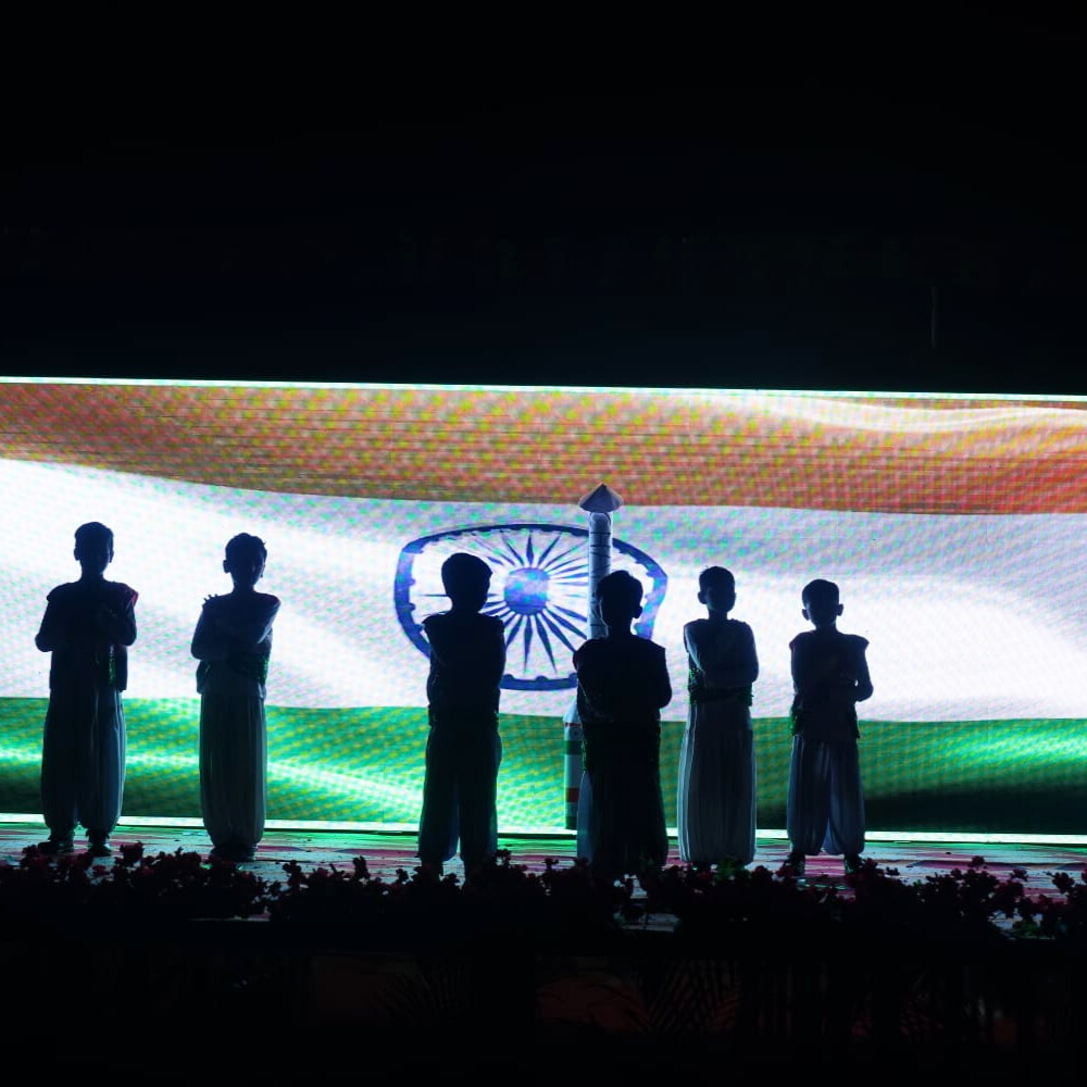 Students performing musical pieces on stage with a live audience at the school music concert.